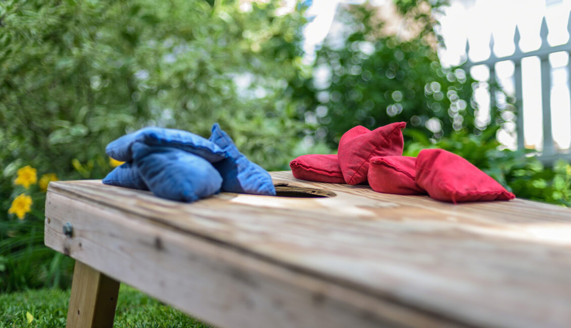red and blue bean bags on cornhole board